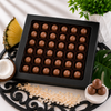 Forty Piña Colada craft chocolate bonbons in a large black window gift box with pineapple, coconut, toasted coconut flakes, and tropical leaf accents.