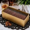 Bomb Confections 30-piece mini bourbon chocolate bars individually wrapped and presented in a premium gold gift box, accented with a crystal whiskey glass and a subtle pecan garnish for an elegant bourbon-inspired presentation.