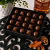 Twenty-piece Bourbon Bonbon Collection by Bomb Confections featuring Buffalo Trace Bourbon and Bourbon Old Fashioned artisan chocolates arranged in a premium black window gift box with bourbon and candied orange accents.