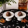 Buffalo Trace Bourbon and Bourbon Old Fashioned artisan bonbons by Bomb Confections displayed on white pedestal stands with bourbon and candied orange accents on a black scroll mat.