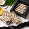 Piña Colada mini chocolate bars with pineapple and toasted coconut in a black gift box