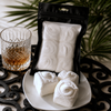 Bomb Confections handmade bourbon marshmallows displayed on a white plate beside a premium black gift pouch, with a Buffalo Trace bourbon bottle, crystal whiskey glass, and elegant cocktail-inspired presentation.