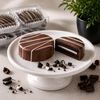 Classic chocolate covered sandwich cookie with white chocolate drizzle, shown whole and cut open to reveal the chocolate cookie and vanilla cream filling on a white pedestal.