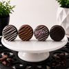 Four chocolate covered sandwich cookies displayed on a white pedestal featuring Classic, Peanut Butter, Birthday Cake, and Dark Chocolate flavors with premium handcrafted chocolate finishes.