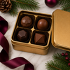 Open gold gift tin with four handcrafted cocktail-inspired bonbons shown in the top layer