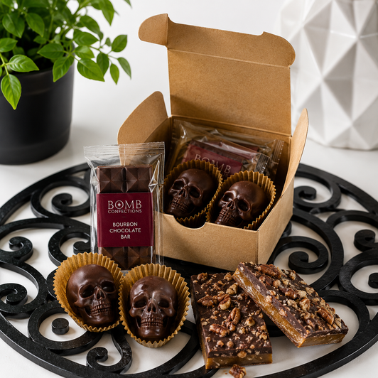 Open Bomb Confections Bourbon Discovery Collection featuring individually wrapped mini bourbon chocolate bars, handcrafted bourbon chocolate skulls, and artisan bourbon pecan toffee arranged in a premium gift box.