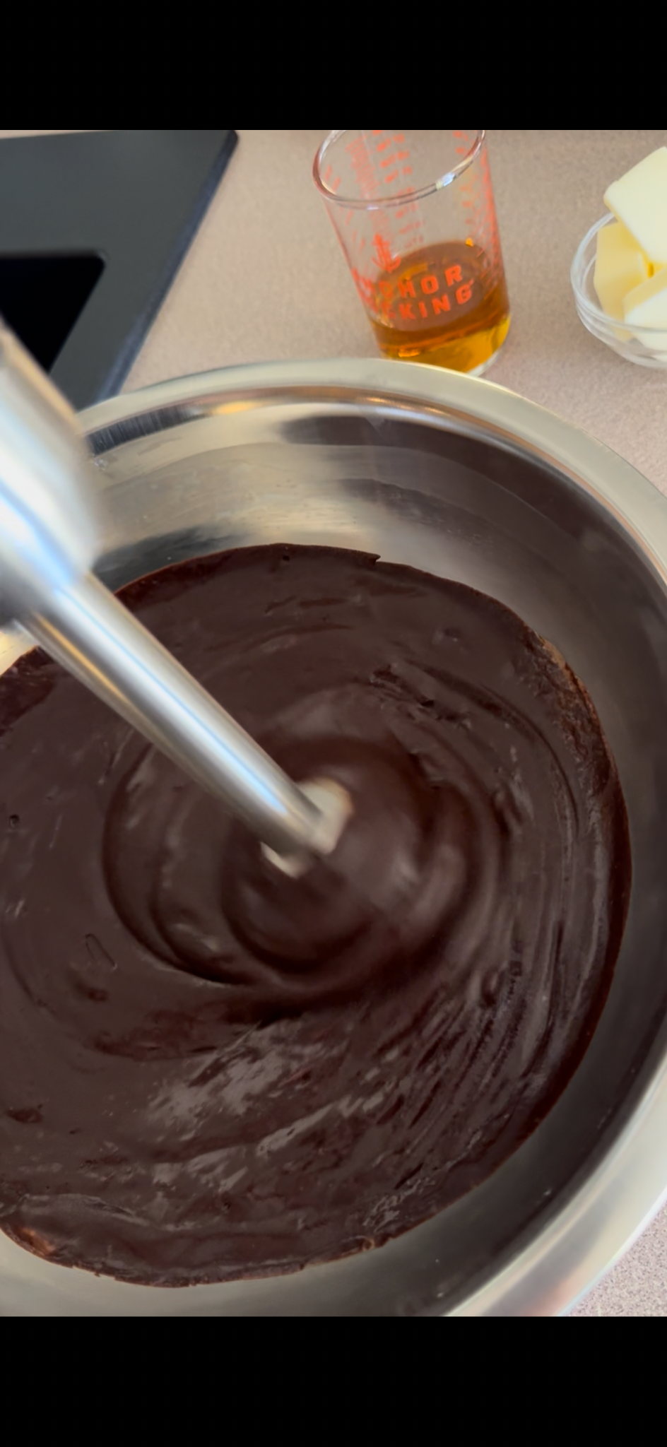 Bourbon measured beside dark chocolate ganache being blended