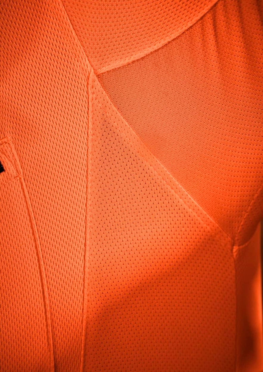An orange short sleeve polo shirt with a textured fabric, featuring a logo on the chest.