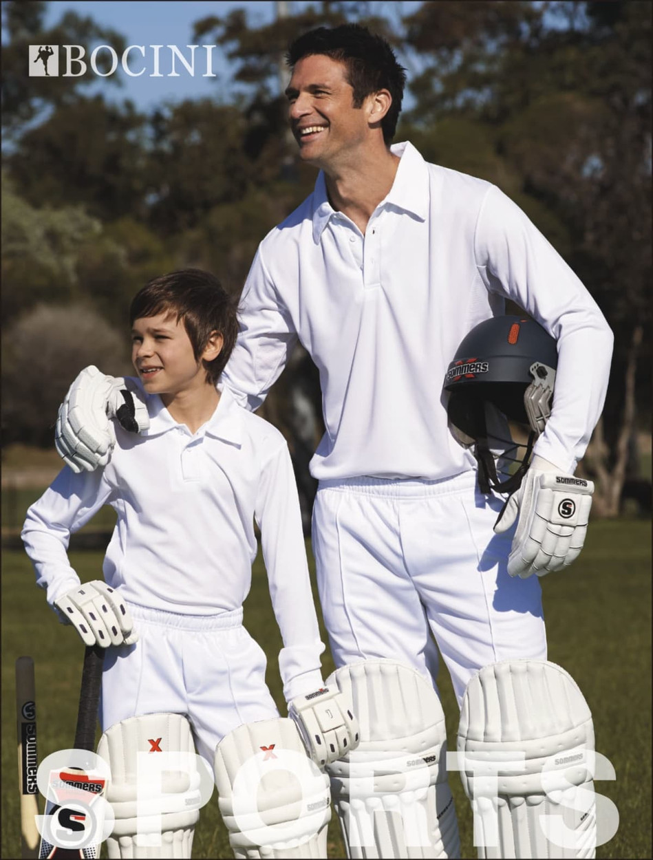 A pair of white cricket pants designed for adults, featured alongside matching gear and players in a grassy field.