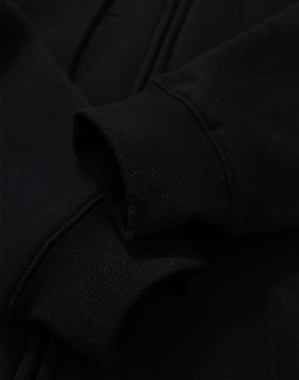 A black men's full-zip fleecy hoodie featuring cuff details and a logo.
