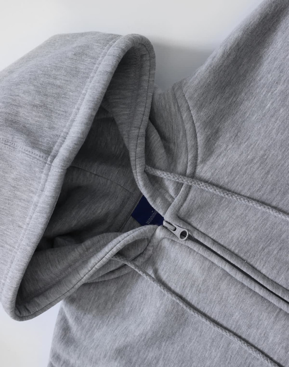 A grey men's full-zip fleecy hoodie with a hood and zippered front. It features a branding logo.
