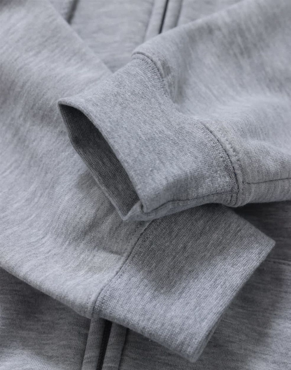 A grey men's full-zip fleecy hoodie with a close-up of the cuffs and fabric texture, featuring a logo.