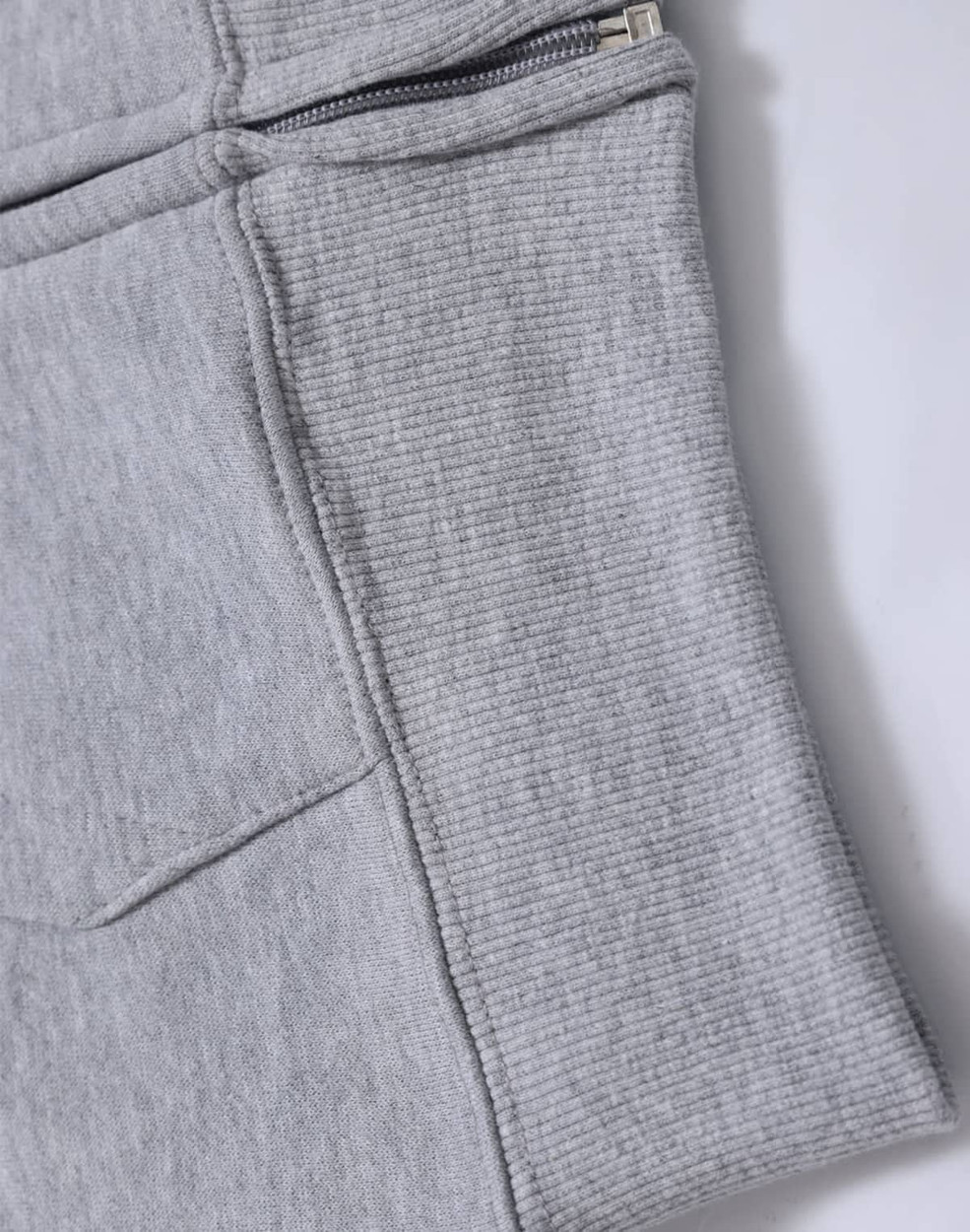 A grey fleecy hoodie featuring a full zip and ribbed cuff detail. It includes pockets and has a logo.
