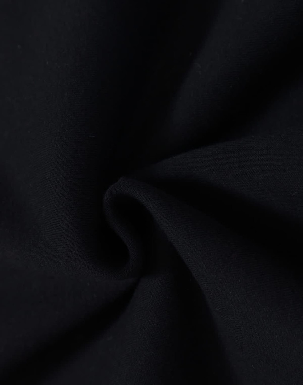 A close-up of black fabric with a soft texture, demonstrating a fleecy material suitable for hoodies.