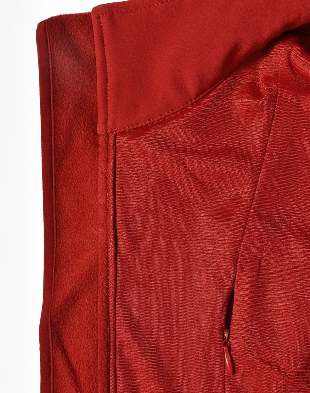 A red softshell vest featuring a smooth exterior and a textured interior, with a zippered pocket and a logo.