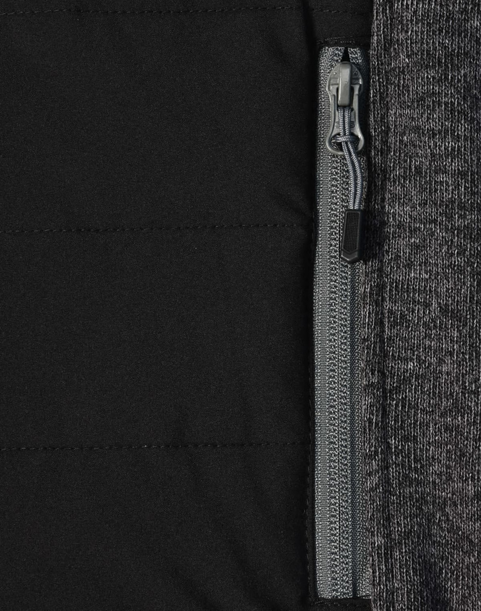 A close-up of a men's jacket featuring a heather sleeve and quilted black body with a zip pocket.