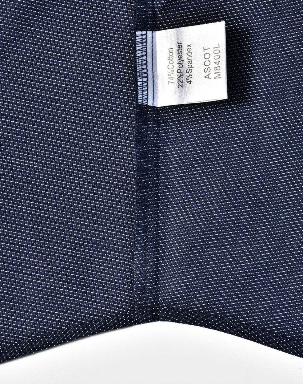 A close-up of a navy pin dot fabric showing a care label. The fabric has a textured, patterned design.