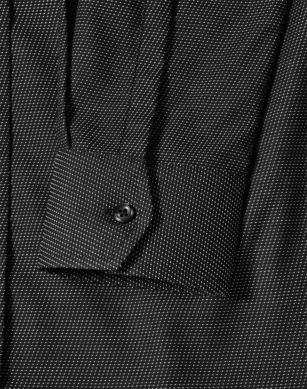 A close-up of a black pin dot stretch long sleeve shirt with a buttoned cuff and subtle pattern details.