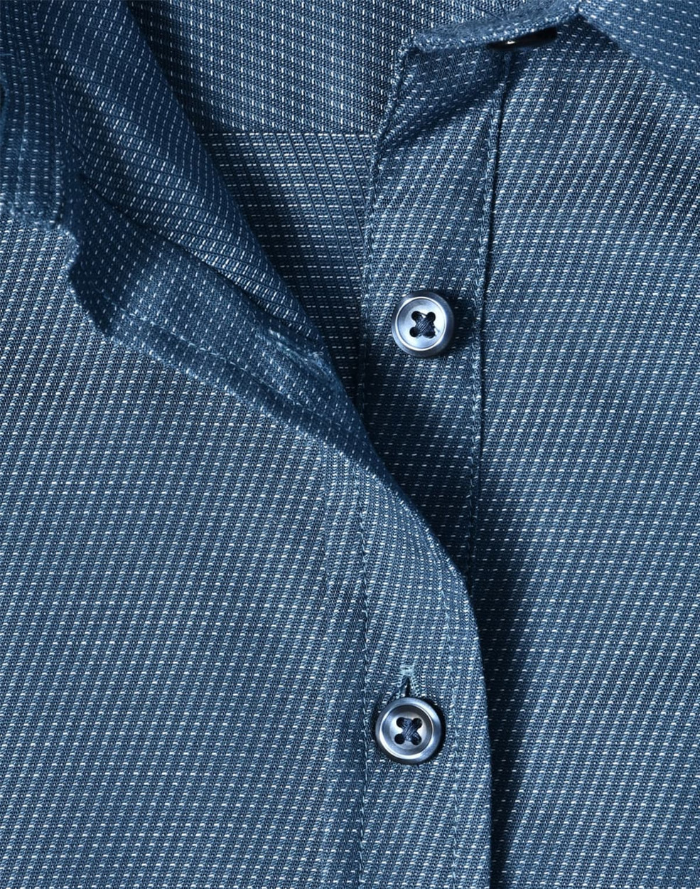 A close-up of a blue pin dot stretch 3/4 sleeve shirt featuring buttons and a fabric texture.