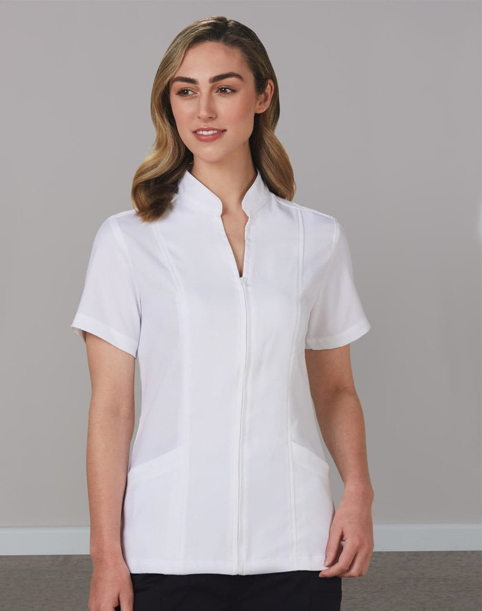 A white women's full zip front tunic with short sleeves and a stand-up collar, featuring a logo.