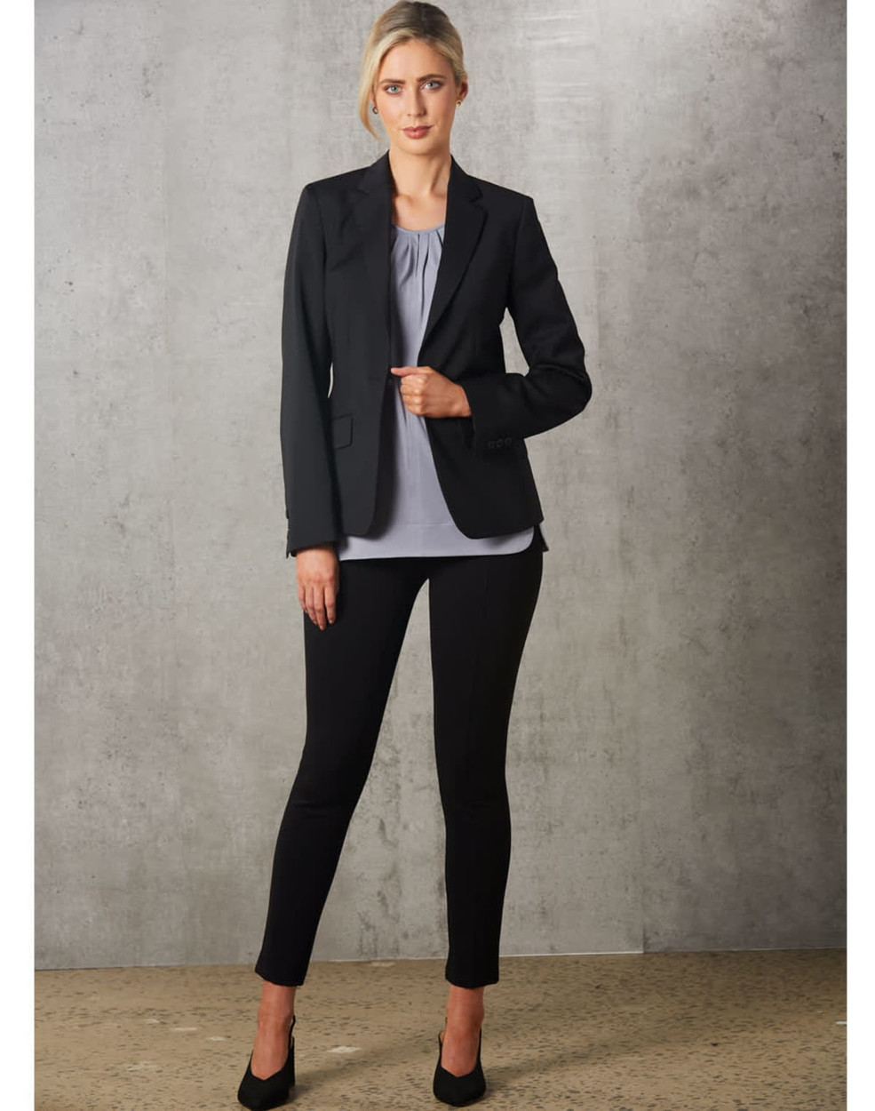 A light grey ladies' round neck top with pleats, paired with a black blazer and black trousers.