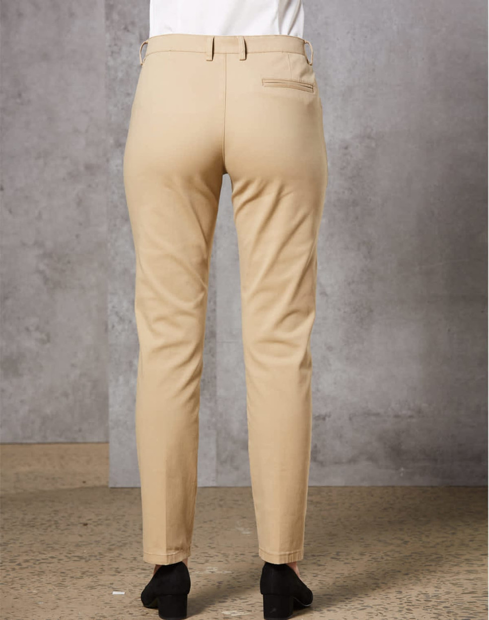 A pair of beige ladies' chino pants seen from the back, featuring a fitted design and a rear pocket.