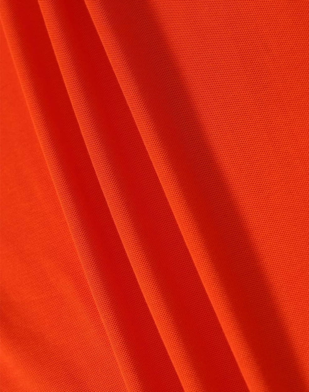 A close-up of orange fabric featuring a textured surface, ideal for polo shirts. The image includes a logo.