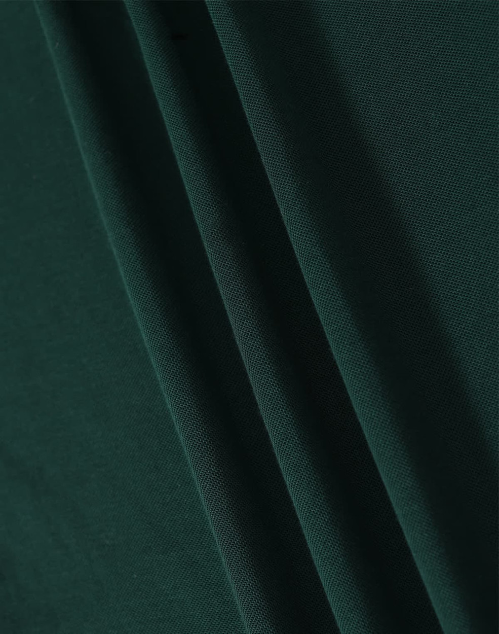 A close-up image of dark green fabric with soft texture, showcasing folds and draping.