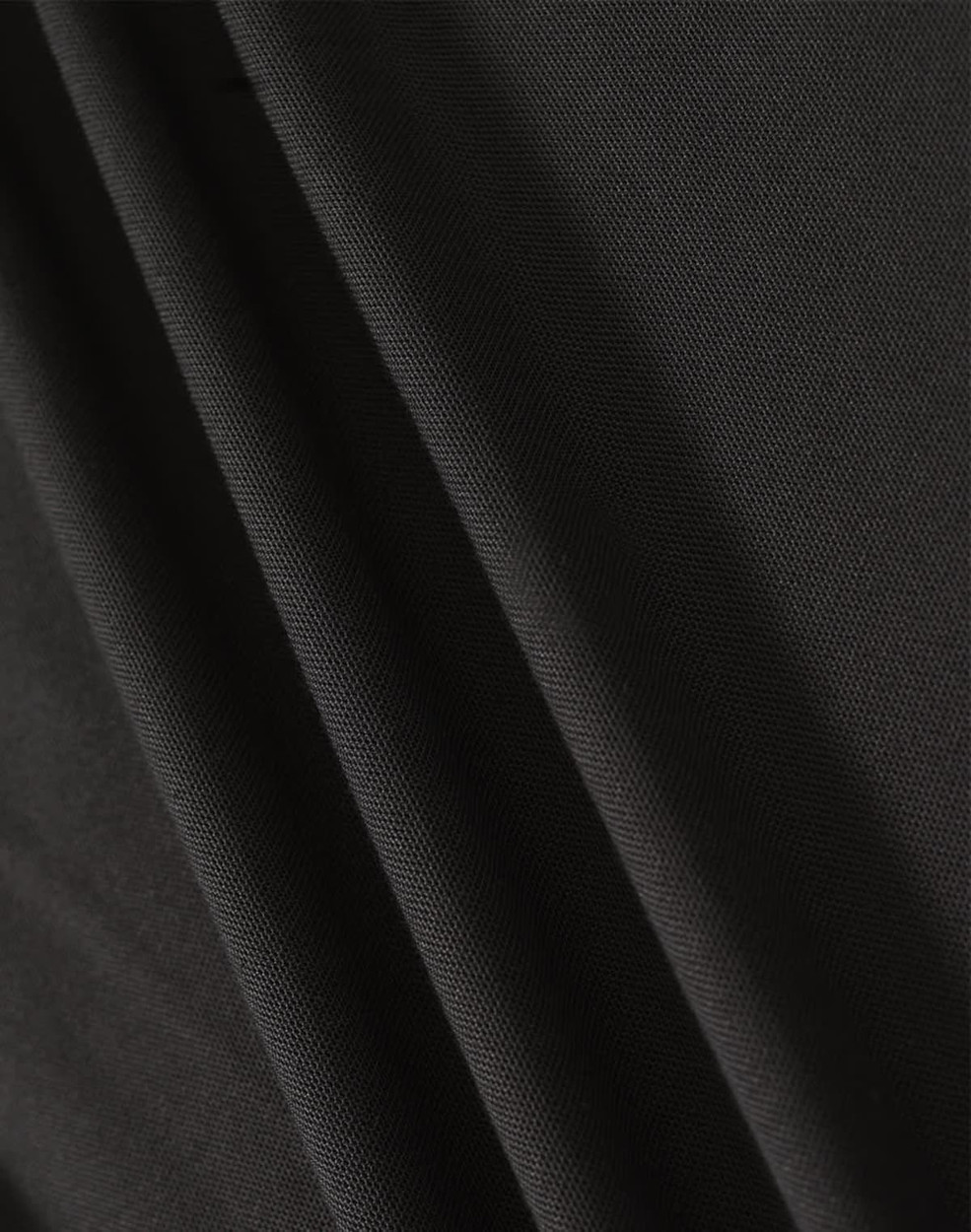 A close-up of black fabric showcasing texture and drape, featuring a subtle weave pattern.
