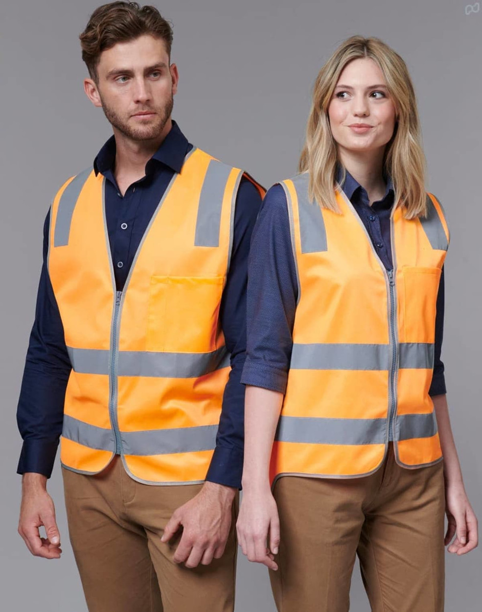 Two individuals wearing bright orange safety vests with reflective stripes, one male and one female, against a neutral background.