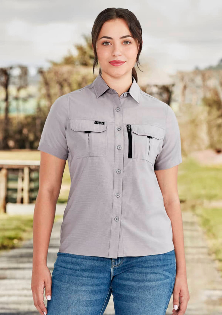 A light grey women's outdoor short sleeve shirt with chest pockets and a zipper pocket, featuring a logo.