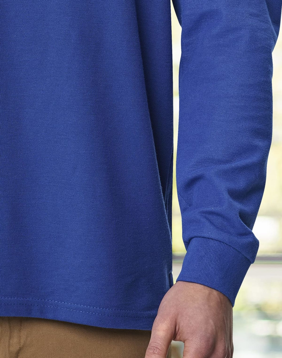 A close-up of a blue unisex long sleeve polo shirt, featuring a simple design and a branded logo.
