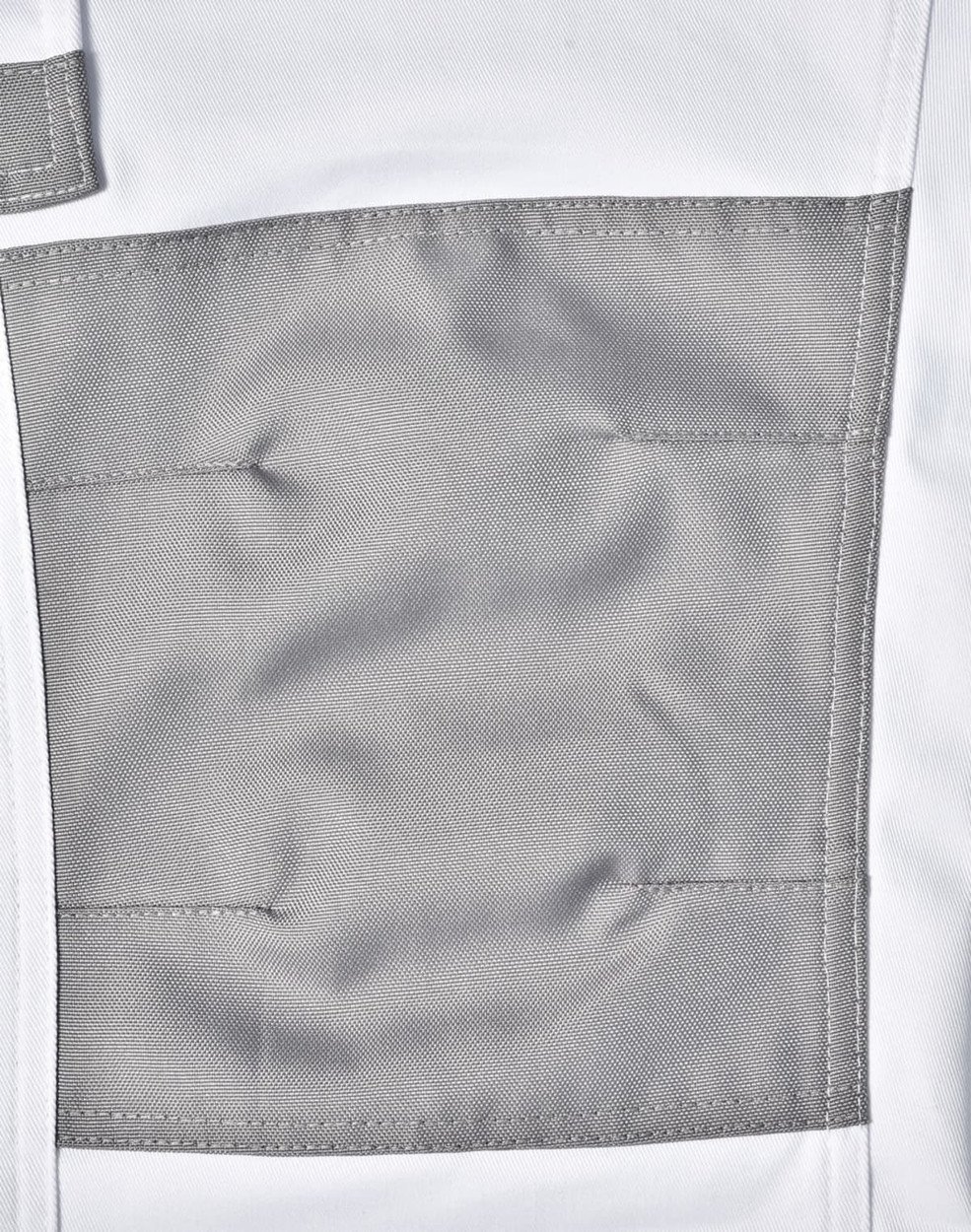 A close-up of unisex utility stretch cargo work pants in white with a grey patch pocket. The pants have a logo detail.