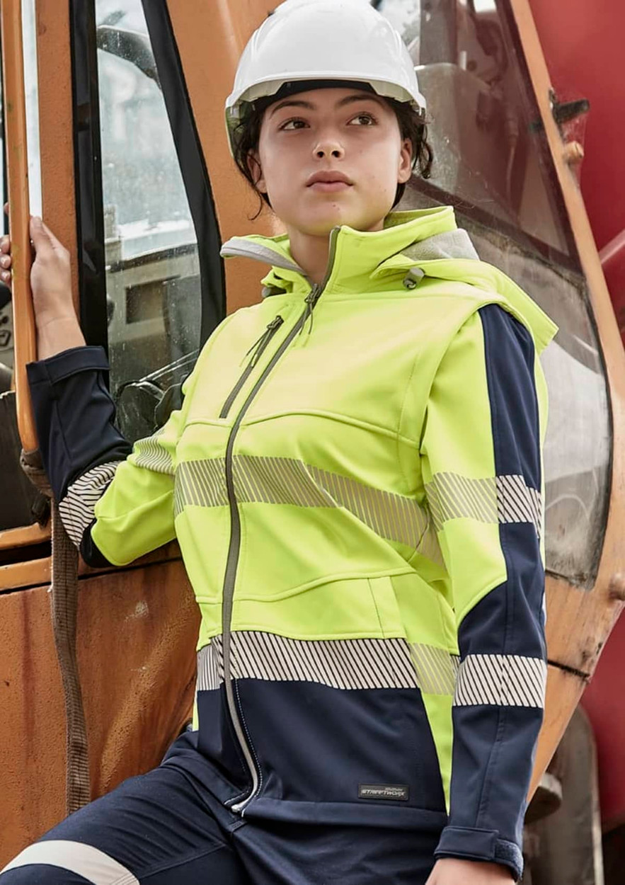 A women's softshell jacket in hi-vis yellow and navy blue, featuring reflective stripes and a hood. It has a logo on the front.