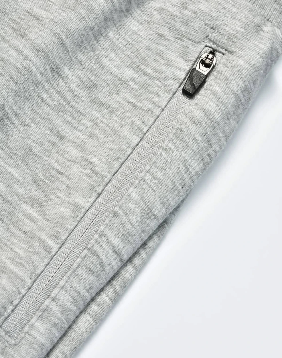 A close-up of grey kids' poly/cotton terry sweat pants featuring a zip pocket and soft fabric texture.