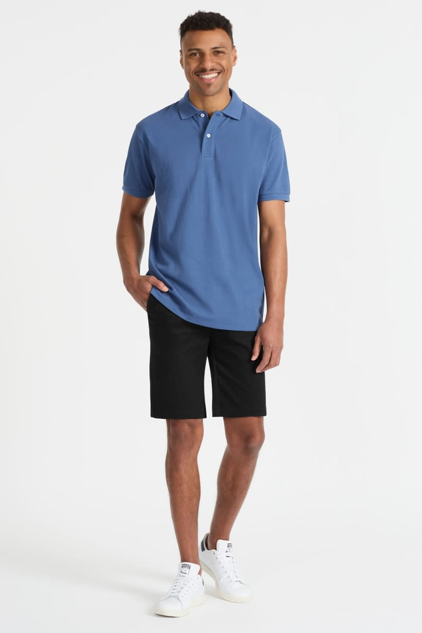 A man wearing a blue polo shirt and black shorts, paired with white sneakers. The shirt features a logo.