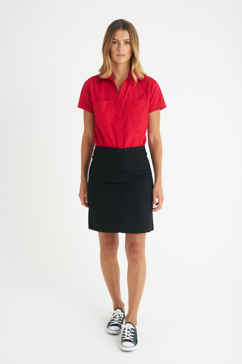 A model wearing a red shirt and a black chino skirt, with a pair of black and white sneakers.