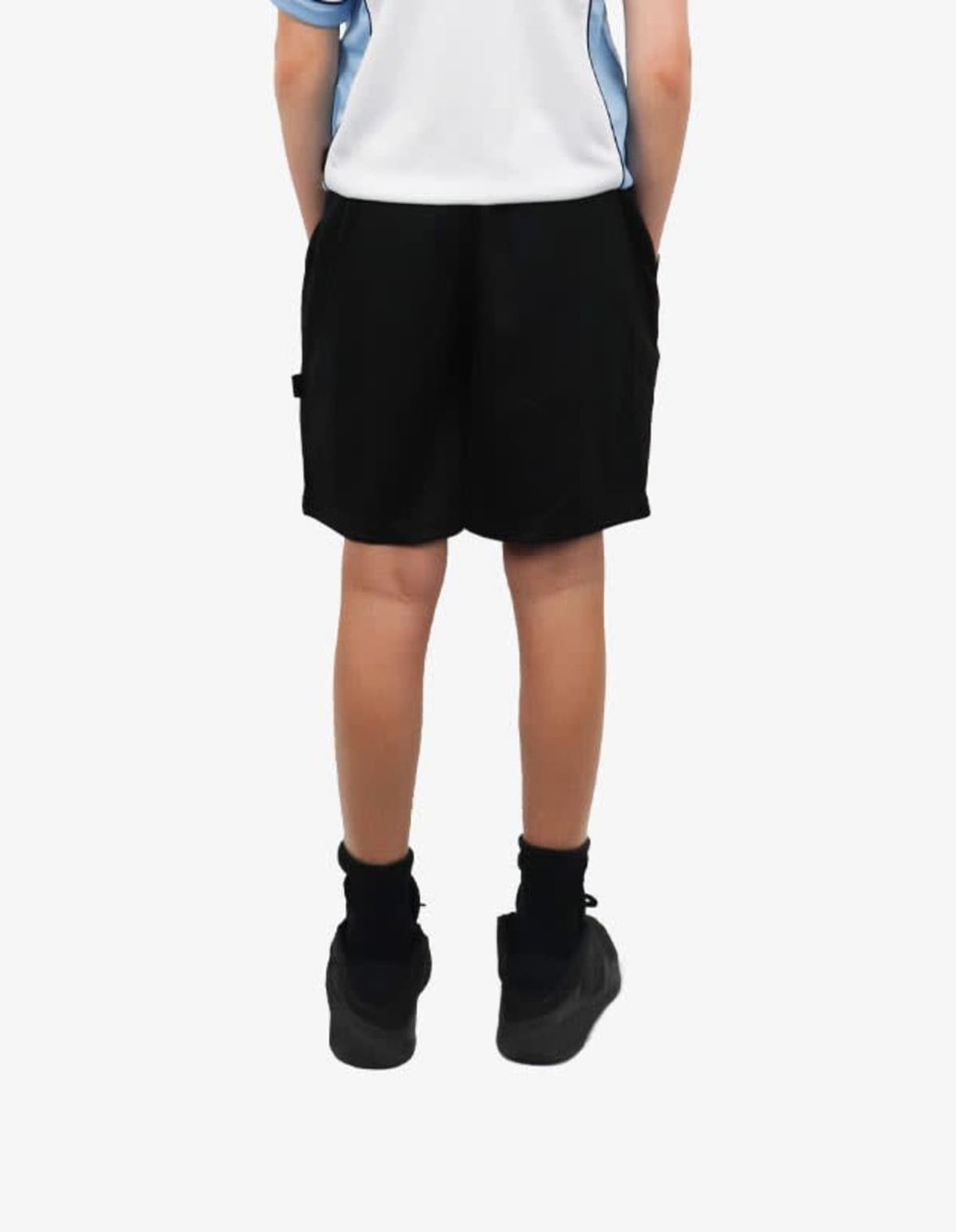 Black sports shorts with pockets, featuring a logo, worn by a child standing with hands in pockets.