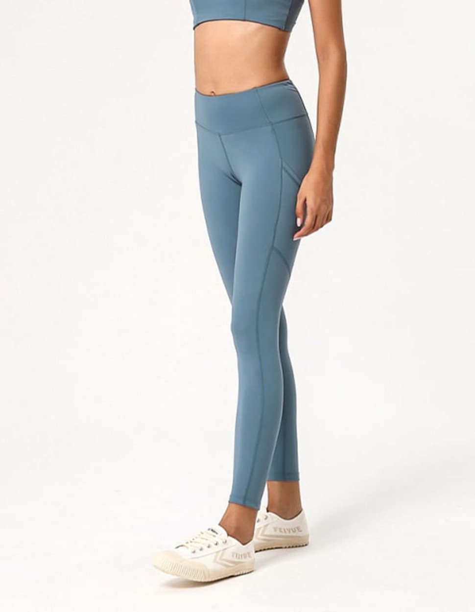 A pair of blue ladies' leggings displayed on a model, featuring a fitted design and a logo.
