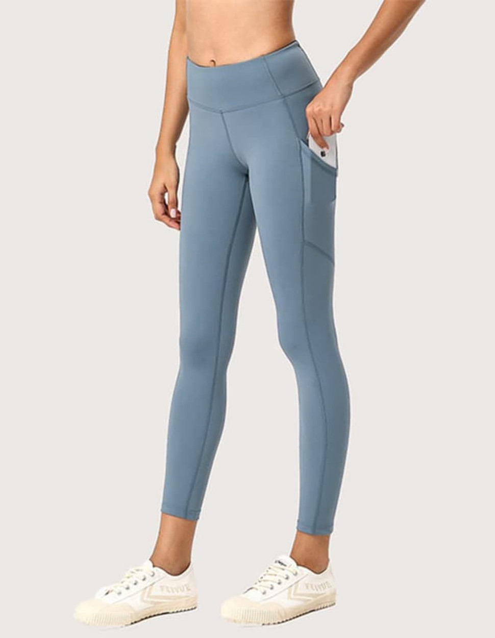A pair of light blue ladies' leggings with a pocket, styled with a fitted design and worn with white sneakers.