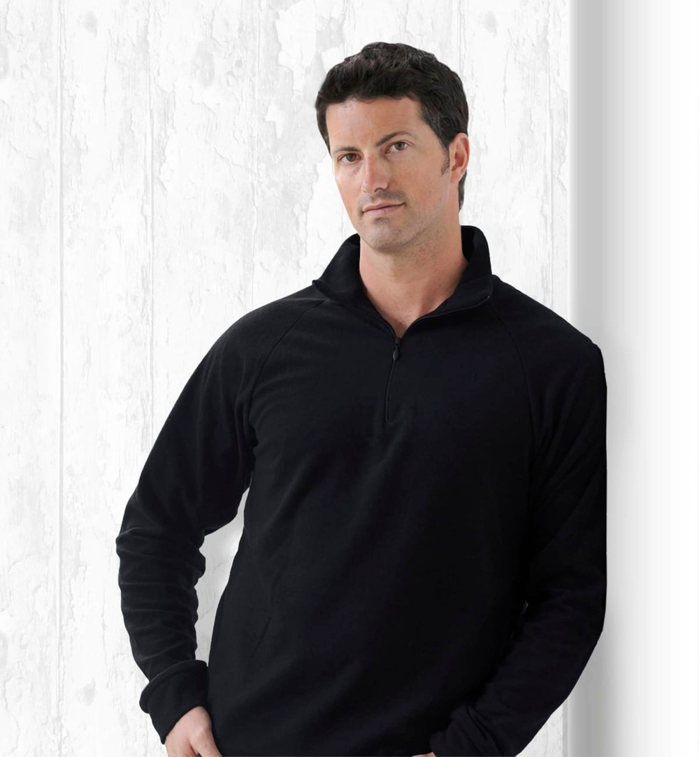 A black jumper with a zip collar, featuring a model standing against a textured white background.