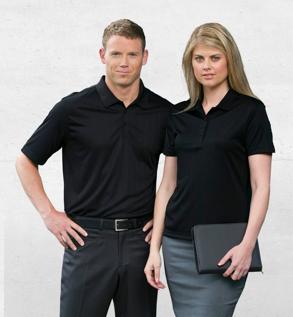 A black men's polo shirt worn by a man and a matching black polo worn by a woman, both with a subtle ribbed design.
