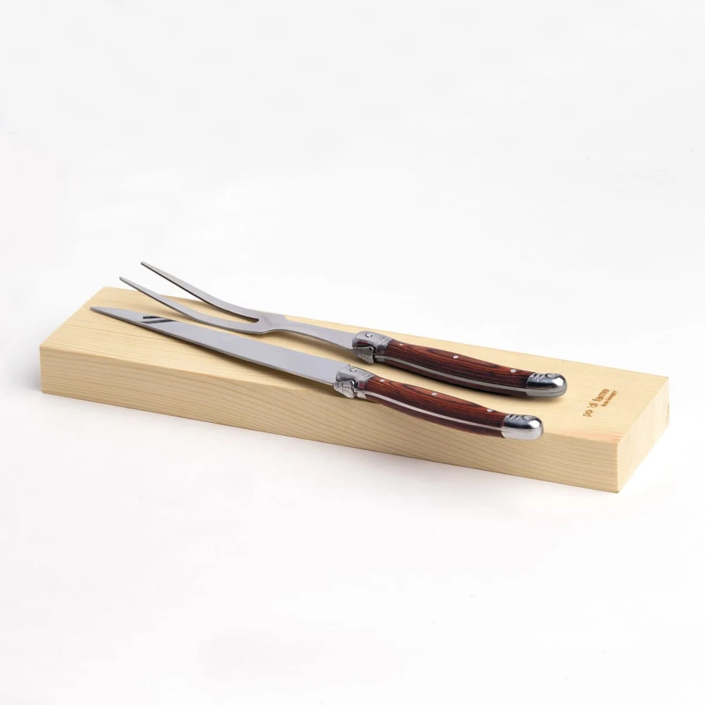 A stainless steel carving set with wooden handles, resting on a wooden presentation box.