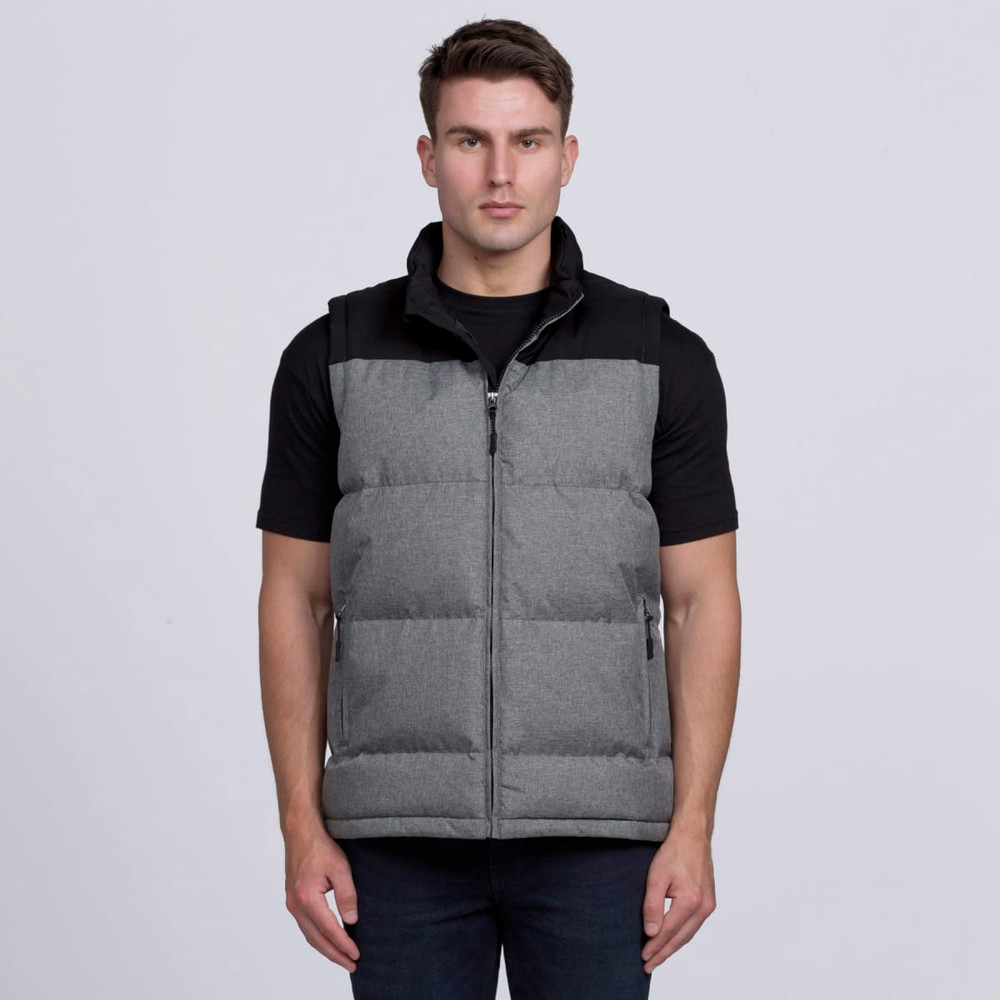 A man wearing a grey puffer vest with a black top. The vest features a zip and side pockets.