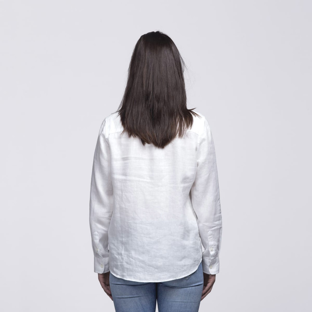 A white linen button-up shirt viewed from the back, worn by a woman with long hair, paired with blue jeans.