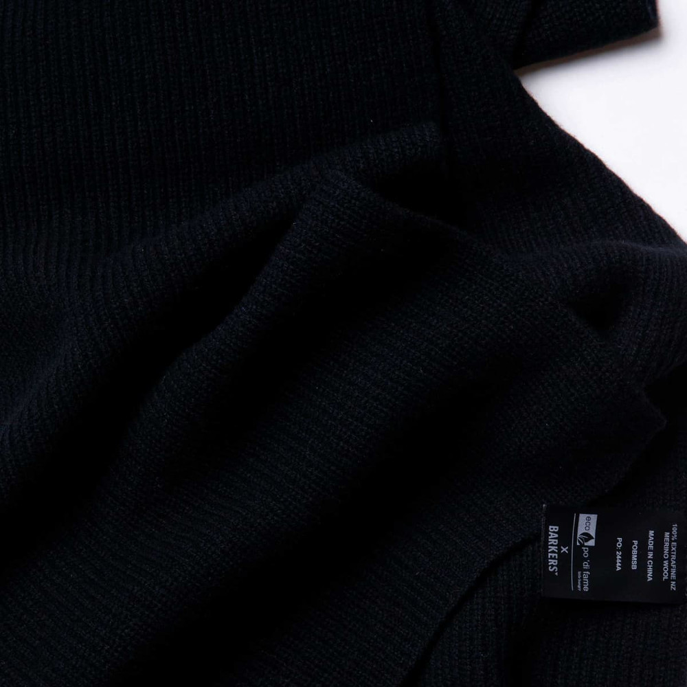 A black 100% Merino scarf, featuring a soft ribbed texture and a label.
