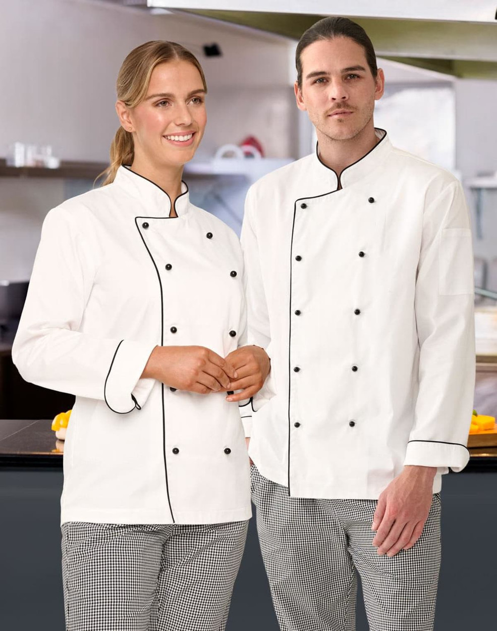 A unisex executive chef jacket in white with black trim, worn by a woman and a man in a kitchen setting.