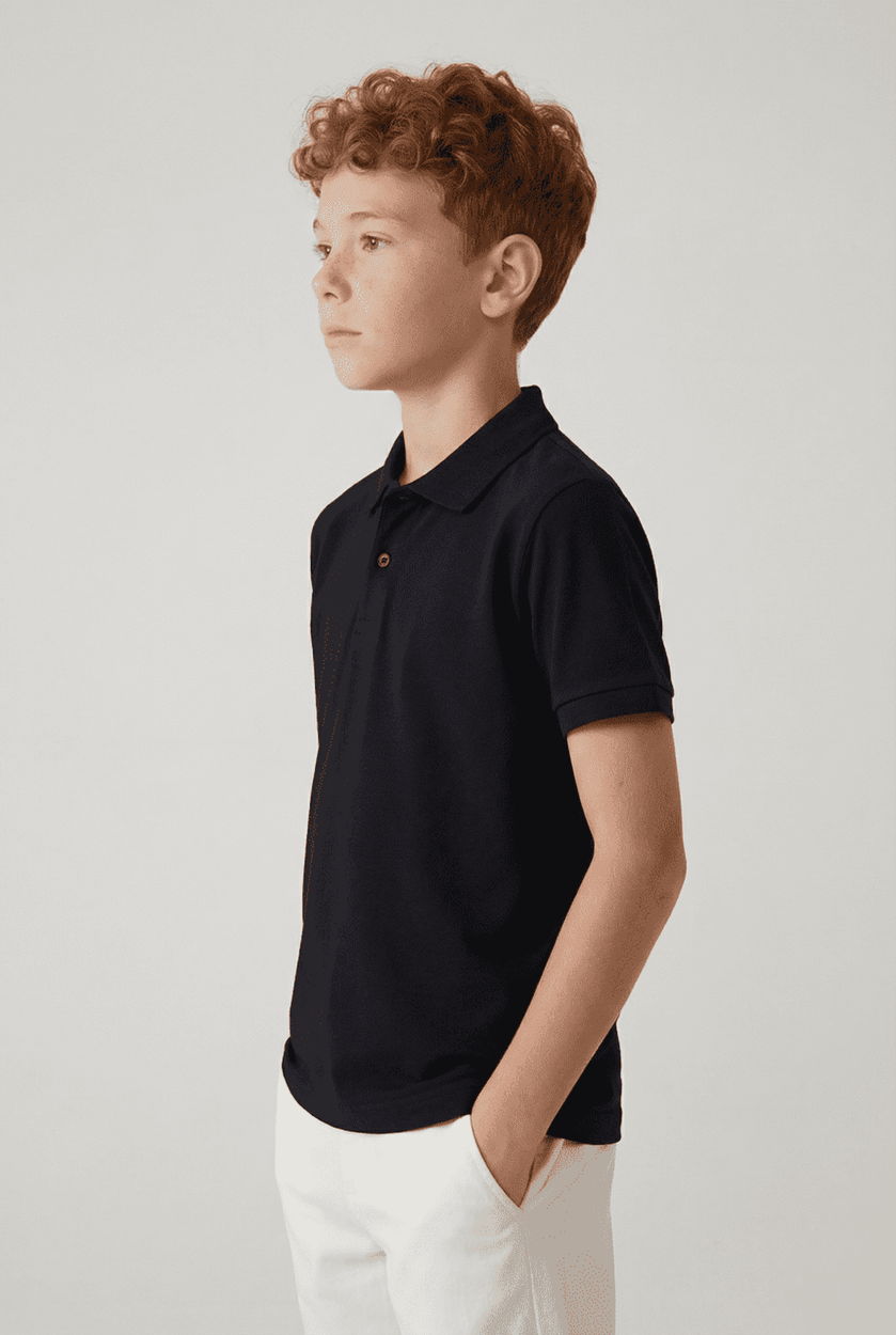A youth polo shirt in navy blue, featuring a collar and a logo, displayed on a model with curly hair.