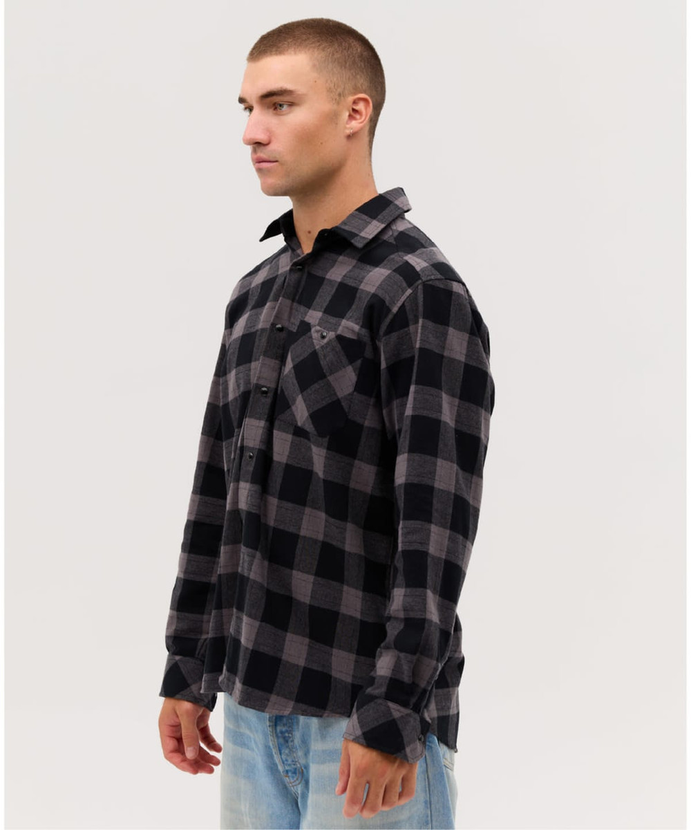A long sleeve, button-up shirt in black and grey checkered pattern. It has a single chest pocket and a logo.