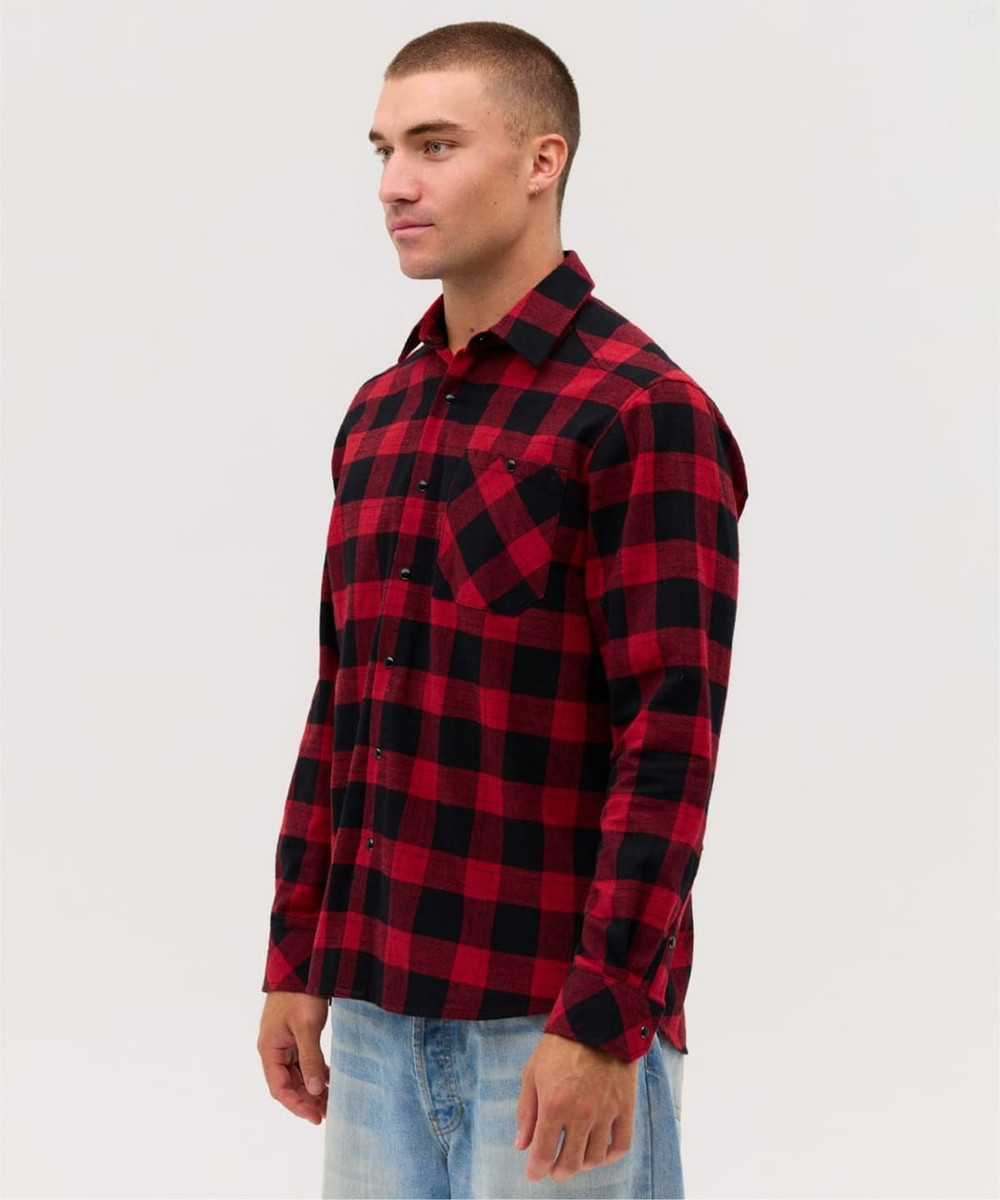 A man wearing a red and black checkered flannel long sleeve shirt, featuring a pocket and button-up design.